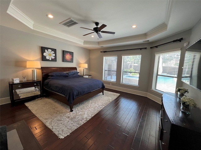 bedroom with dark hardwood / wood-style flooring, a tray ceiling, ornamental molding, and ceiling fan