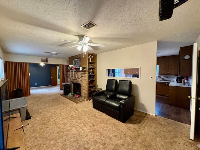 carpeted living room with a textured ceiling, ceiling fan, and a fireplace