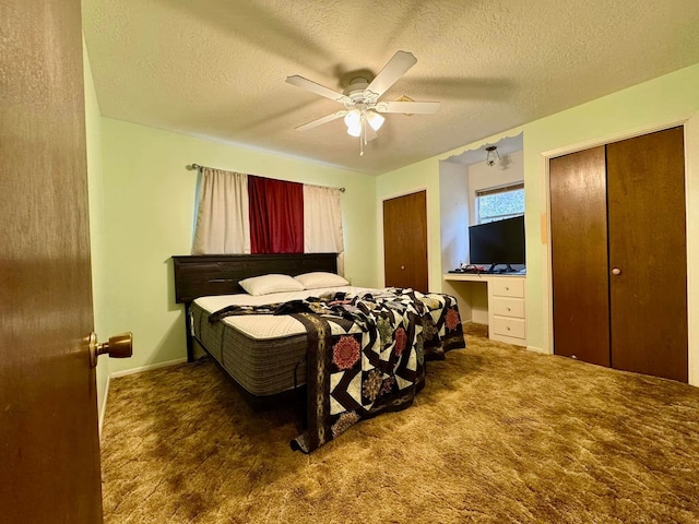 carpeted bedroom with ceiling fan, a textured ceiling, and multiple closets