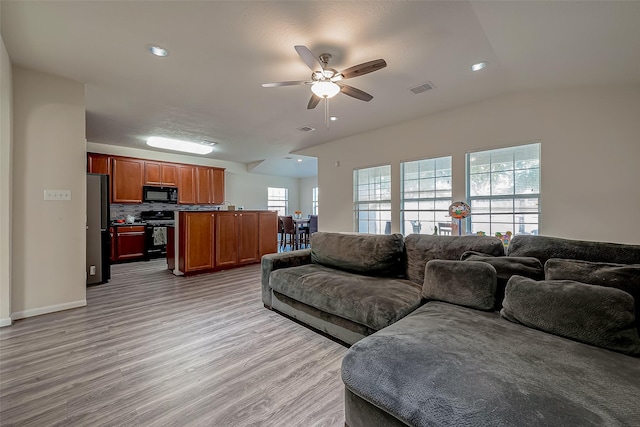 living room featuring ceiling fan, lofted ceiling, and light hardwood / wood-style flooring