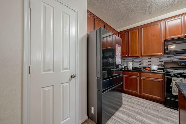 kitchen with a textured ceiling, light wood-type flooring, tasteful backsplash, and black appliances