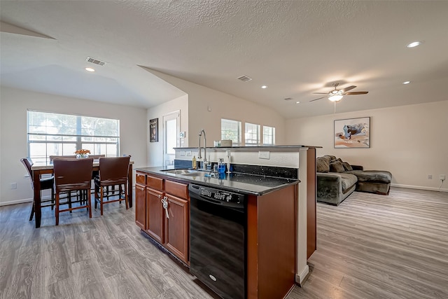 kitchen featuring sink, light wood-type flooring, black dishwasher, and vaulted ceiling