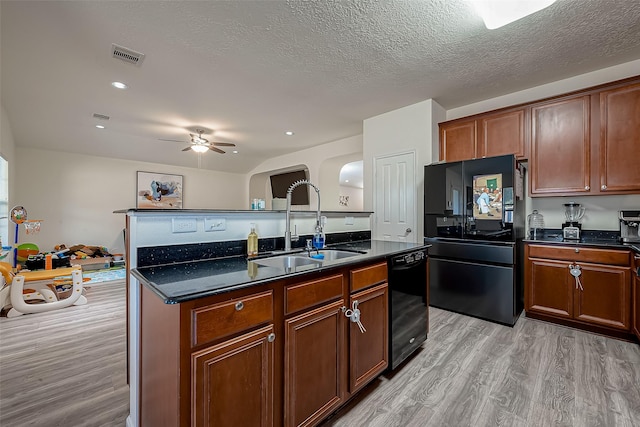 kitchen featuring a textured ceiling, sink, black appliances, a center island with sink, and light hardwood / wood-style floors