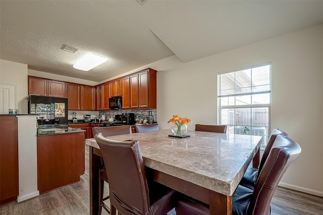 kitchen with hardwood / wood-style floors, refrigerator, backsplash, and a breakfast bar area