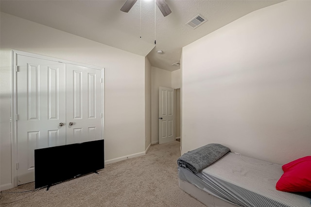 bedroom with ceiling fan, a closet, light colored carpet, and lofted ceiling