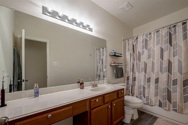 full bathroom with vanity, a textured ceiling, shower / bath combo with shower curtain, hardwood / wood-style floors, and toilet