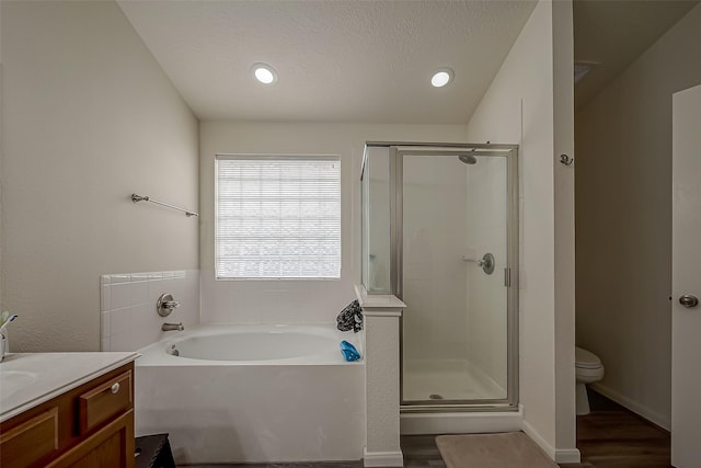 full bathroom with vanity, toilet, a textured ceiling, independent shower and bath, and wood-type flooring