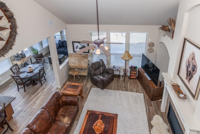 living room with light hardwood / wood-style floors, ceiling fan, and lofted ceiling