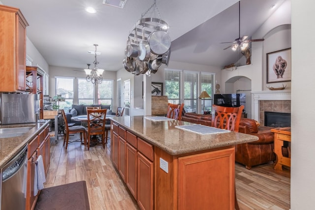 kitchen with stainless steel dishwasher, a kitchen island, light hardwood / wood-style flooring, and a tiled fireplace