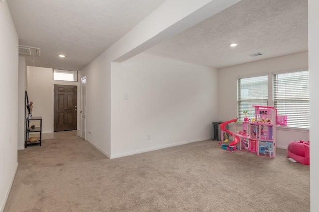 game room with light carpet and a textured ceiling