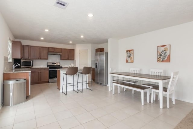 kitchen with a breakfast bar, a center island, light tile patterned floors, and stainless steel appliances