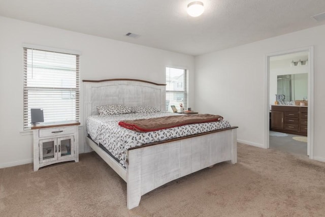 bedroom with multiple windows, ensuite bathroom, and carpet floors