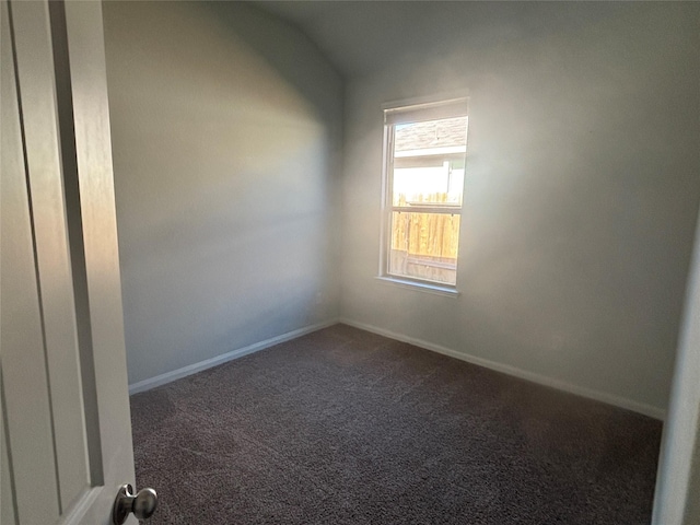 unfurnished room with dark carpet and vaulted ceiling