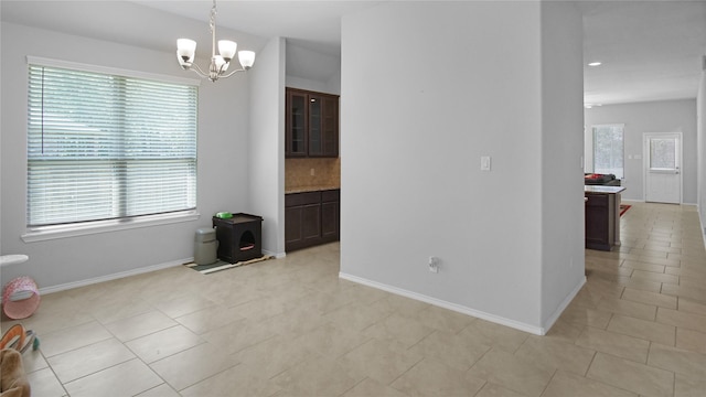 tiled empty room featuring a notable chandelier