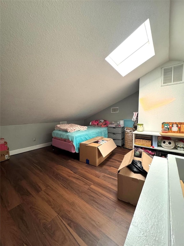 bedroom featuring a textured ceiling, dark wood-type flooring, and vaulted ceiling with skylight