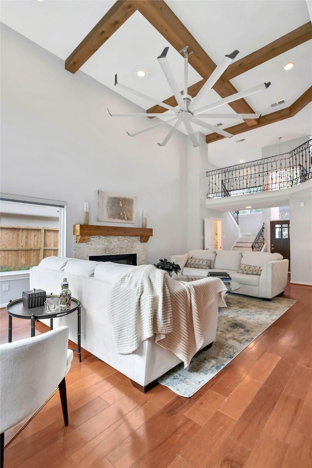 living room featuring beam ceiling, a fireplace, plenty of natural light, and hardwood / wood-style flooring