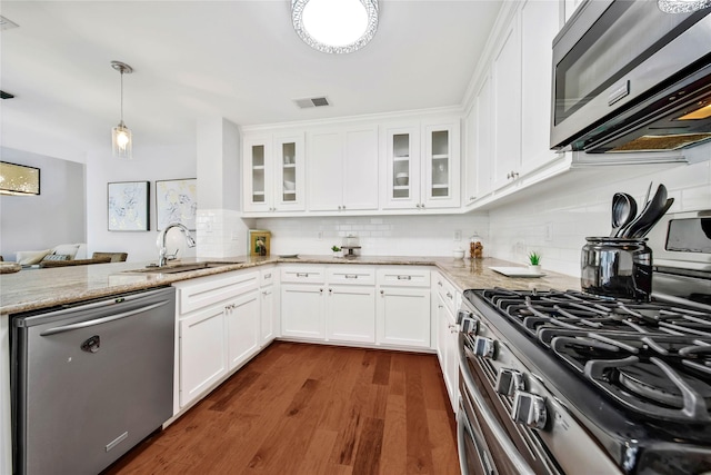 kitchen with pendant lighting, light stone counters, white cabinetry, and appliances with stainless steel finishes