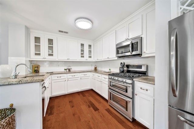 kitchen featuring light stone countertops, decorative backsplash, stainless steel appliances, sink, and white cabinetry