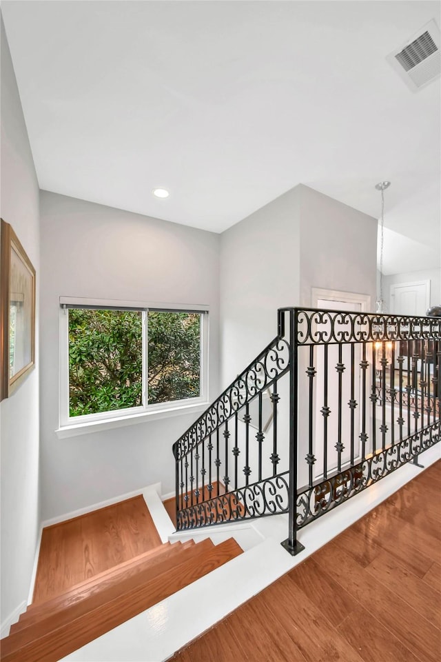 stairs with hardwood / wood-style floors and an inviting chandelier