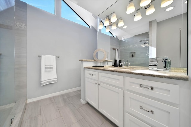 bathroom with a tile shower, vanity, and vaulted ceiling