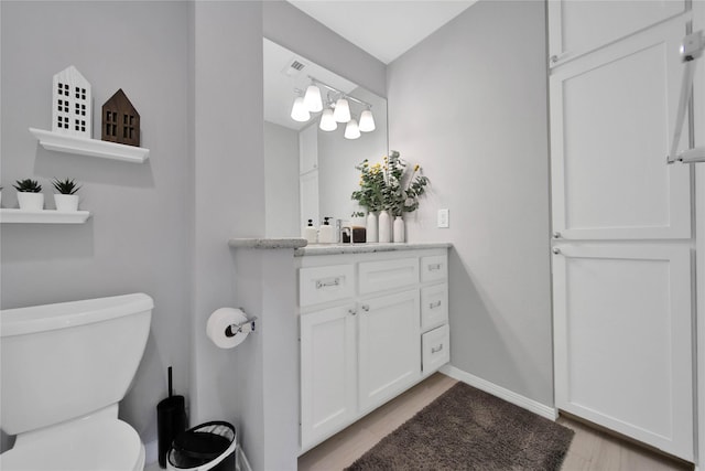 bathroom with hardwood / wood-style floors, vanity, and toilet