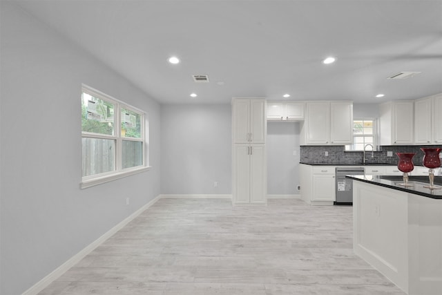 kitchen with stainless steel dishwasher, a healthy amount of sunlight, white cabinetry, and sink