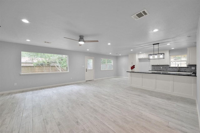 unfurnished living room with ceiling fan, light hardwood / wood-style flooring, and sink