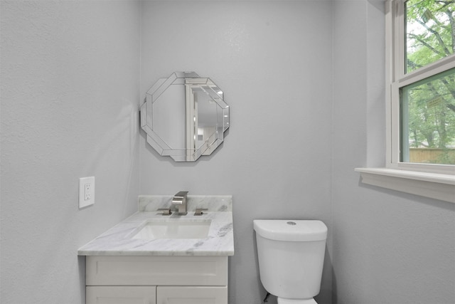 bathroom featuring vanity, a healthy amount of sunlight, and toilet