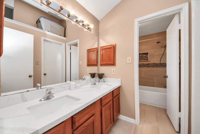 bathroom with vaulted ceiling, tiled shower / bath, and vanity