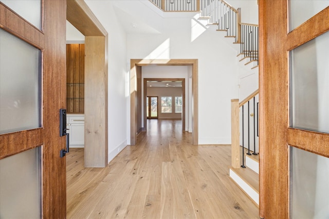 corridor with light hardwood / wood-style floors and a high ceiling