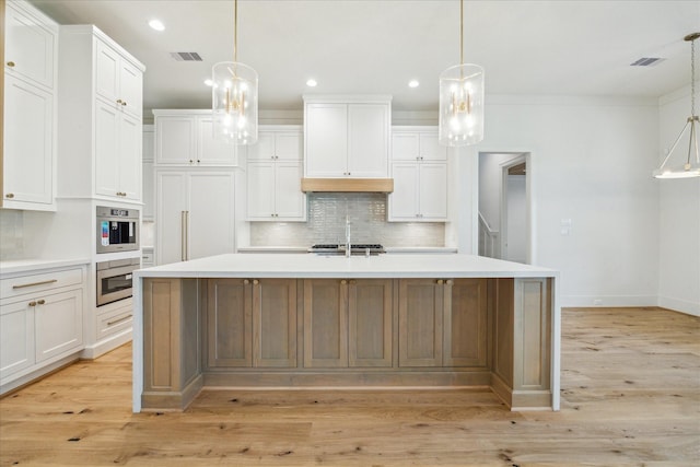 kitchen with light wood finished floors, tasteful backsplash, visible vents, white cabinets, and light countertops