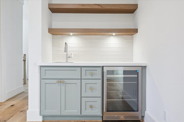 bar with gray cabinets, sink, beverage cooler, and light hardwood / wood-style floors