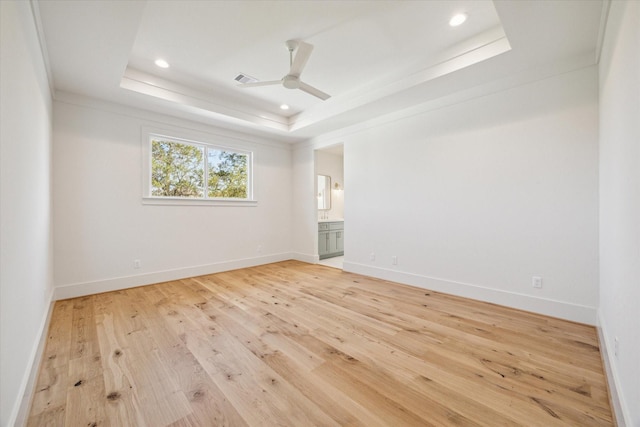 unfurnished room with a tray ceiling, ornamental molding, ceiling fan, and light wood-type flooring