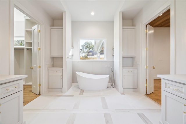 full bath with a soaking tub, recessed lighting, and vanity