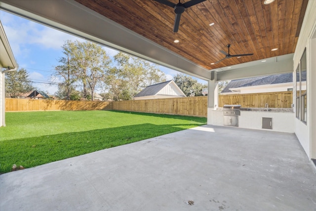 view of patio / terrace with exterior kitchen, a fenced backyard, ceiling fan, and grilling area