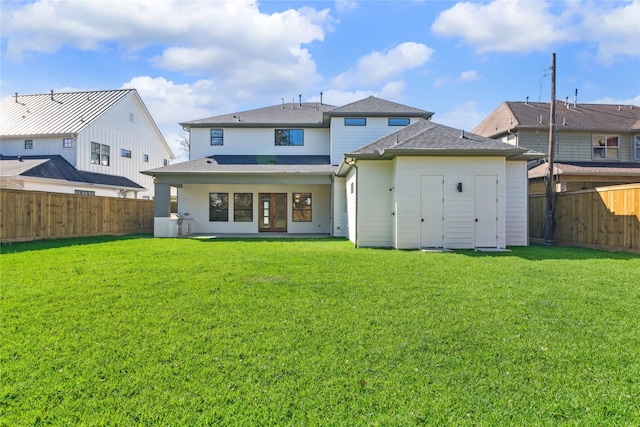 rear view of house featuring a yard and a fenced backyard