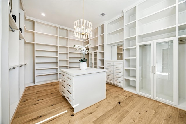 walk in closet with visible vents, a notable chandelier, and light wood finished floors