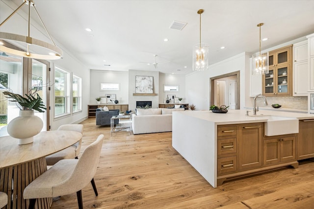 kitchen with visible vents, light wood-style flooring, light countertops, a fireplace, and a sink