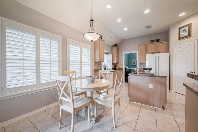 dining room featuring sink, light tile patterned floors, and lofted ceiling