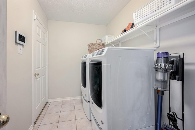 clothes washing area with a textured ceiling, light tile patterned floors, and separate washer and dryer