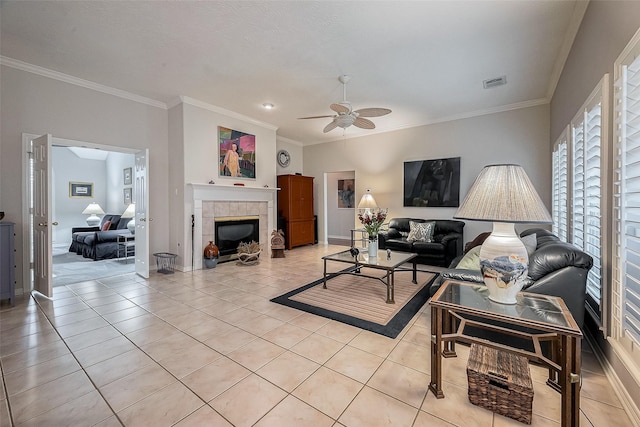 tiled living room featuring ceiling fan, crown molding, and a fireplace