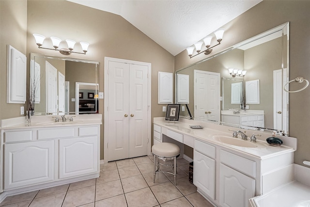 bathroom featuring vanity, vaulted ceiling, tile patterned floors, and a textured ceiling