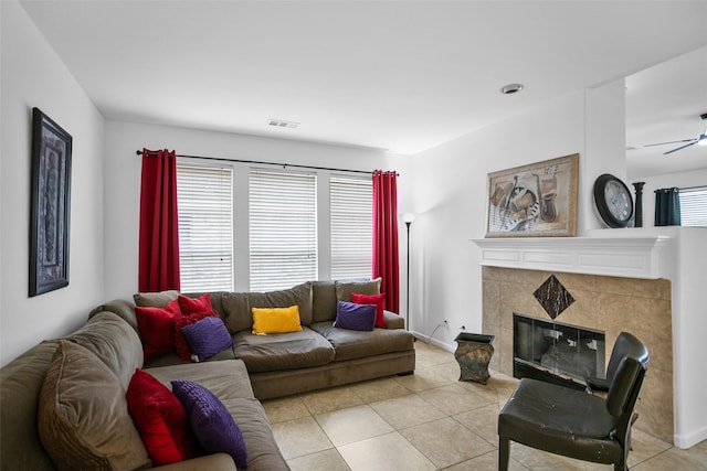 living room with a tile fireplace, ceiling fan, and light tile patterned flooring