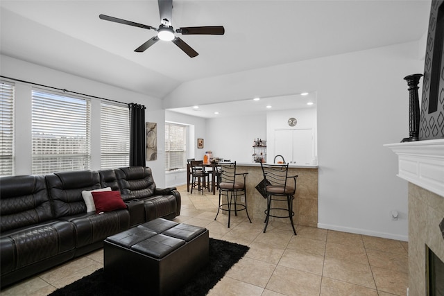 living room featuring vaulted ceiling, light tile patterned floors, a wealth of natural light, and a tiled fireplace