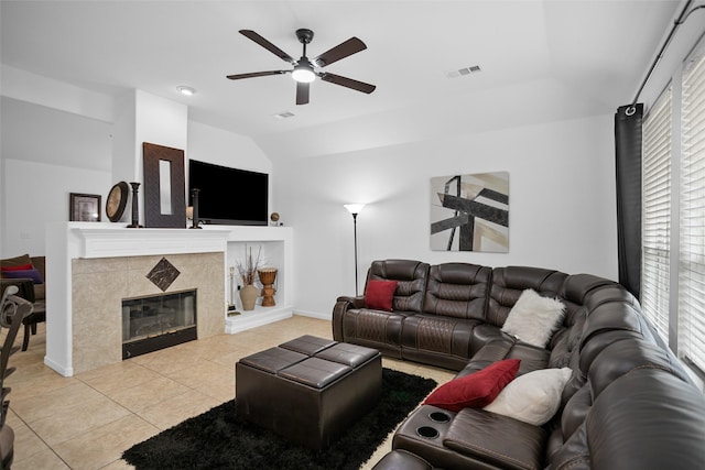 living room with a tiled fireplace, ceiling fan, light tile patterned floors, and vaulted ceiling