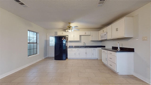 kitchen with black fridge, ceiling fan, sink, light tile patterned floors, and white cabinets