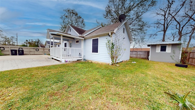 rear view of property with a storage shed, a patio area, and a lawn