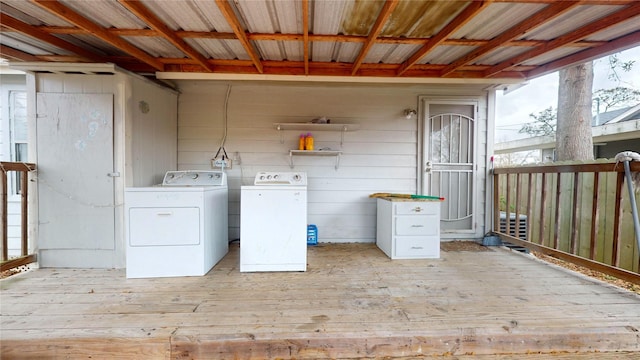 laundry area featuring light hardwood / wood-style flooring, wood walls, and washing machine and clothes dryer