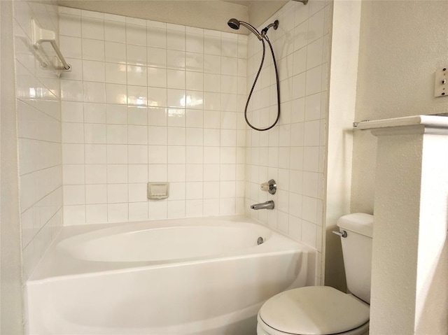 bathroom with tiled shower / bath combo and toilet