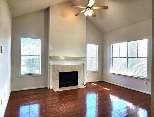 unfurnished living room featuring lofted ceiling, ceiling fan, a healthy amount of sunlight, and a tiled fireplace